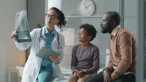 Pediatra-Explicando-El-Escaneo-De-Rayos-X-Al-Hombre-Negro-Y-Su-Pequeño-Hijo